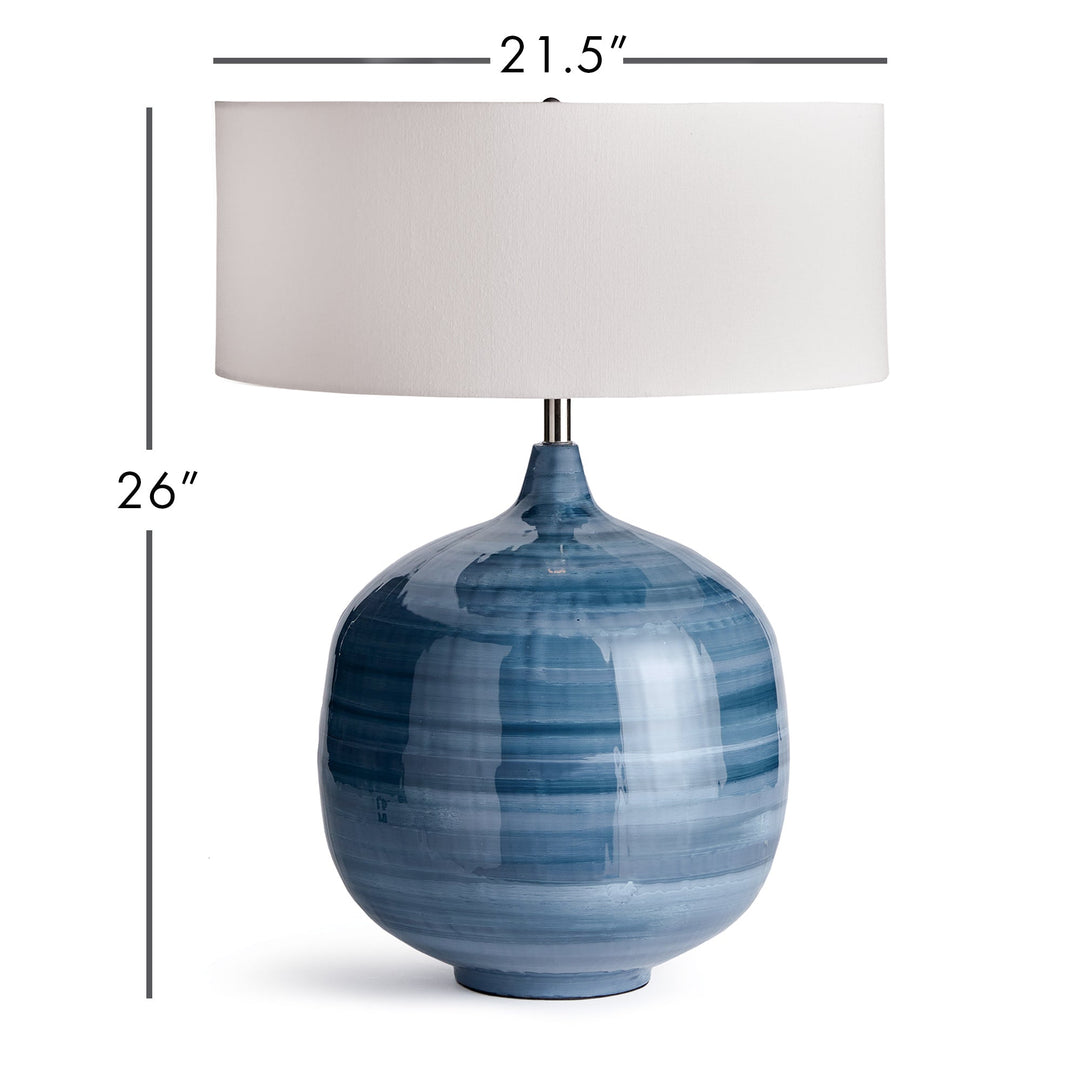 This blue table lamp features a unique design made of enameled iron and hand-painted for a lightweight yet elegant look. The horizontal swirl design adds a touch of refinement, while the oversized linen shade completes the modern aesthetic. A perfect addition to any contemporary living or dining space.