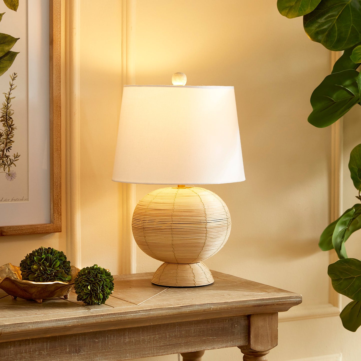 Handcrafted from whitewashed cane rattan, each hourglass table lamp features a distinctive color variation, making it truly one-of-a-kind. Its wide cylindrical white shade adds the perfect touch to any bedroom, living room, or study, solidifying its status as a timeless accent piece.