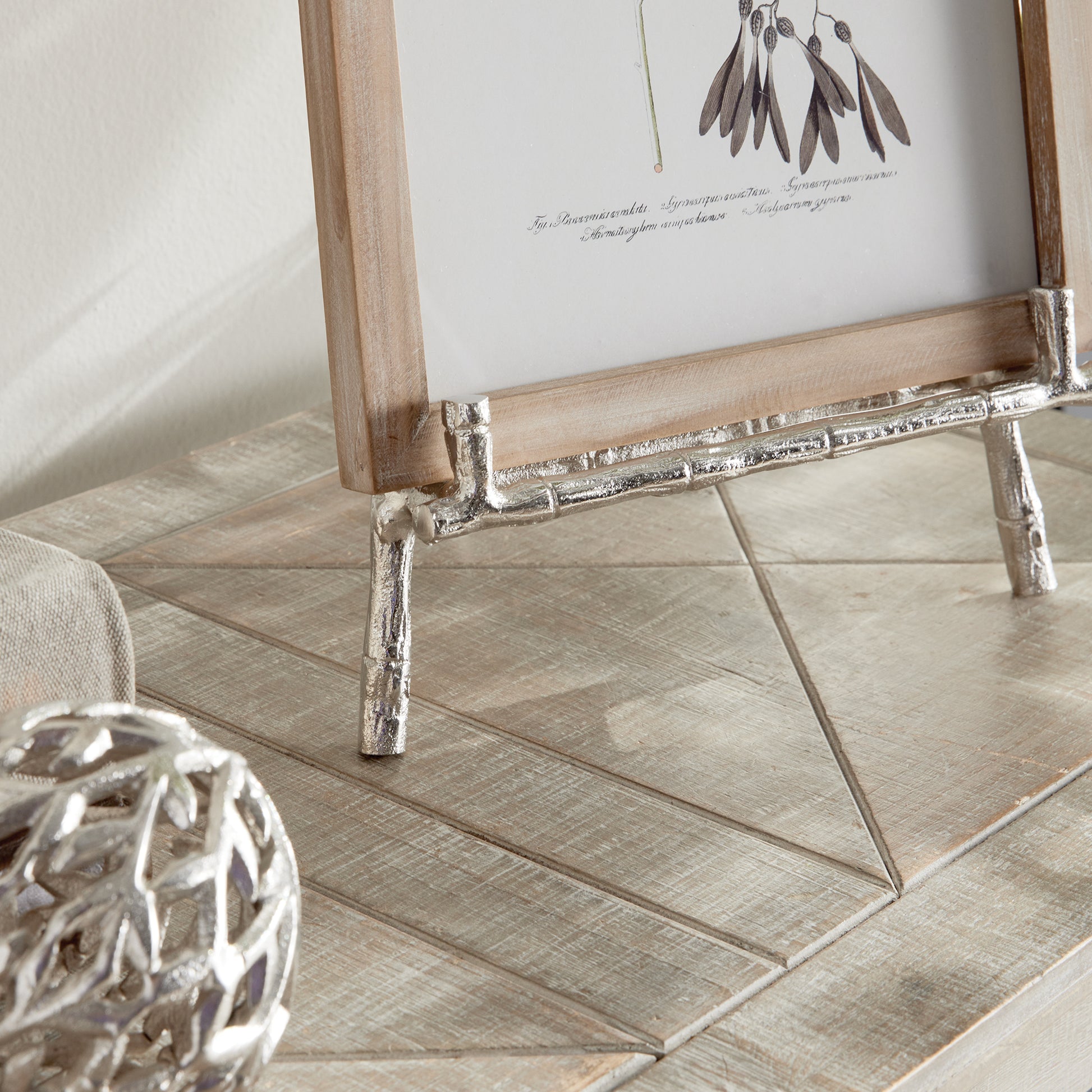 Elevate your decor with this sturdy and resilient silver easel, expertly crafted to exhibit platters, cookbooks, or small art pieces. The traditional aesthetic of bamboo-like silver details adds a timeless charm, while the versatile design allows for effortless display of various items.