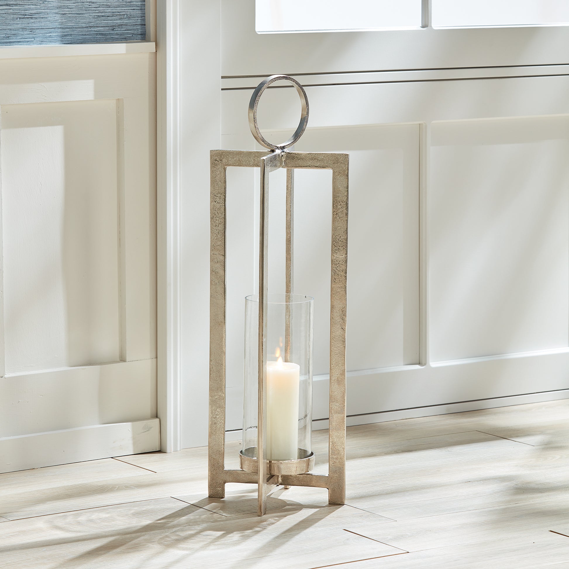 The lantern exudes a sense of grandeur and contemporary style, sure to make a striking impact. It boasts a footed design that elevates your candle and a sizable round handle, making it a great addition to a mantle, front entry, or any space. Meticulously crafted with a modern touch and exceptional attention to detail, this lantern is a standout piece.