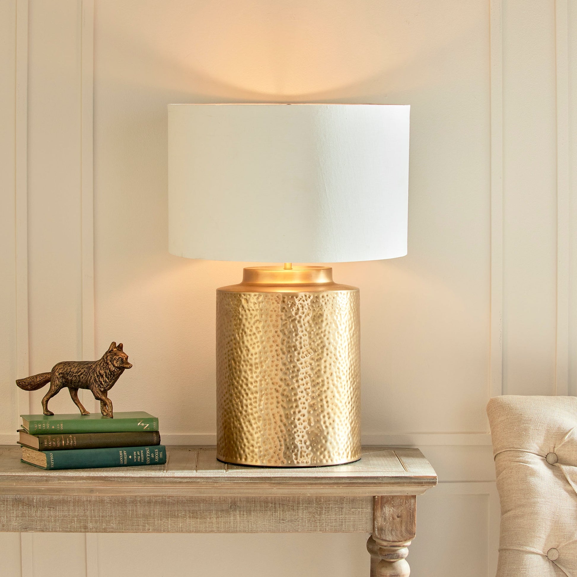 The Keegan Brass Table Lamp makes an impressive statement with its textured brass base and generous size, making it the perfect centerpiece for any space. The bold contrast is heightened by the white gallery shade with a gold inner shade, resulting in a striking and dramatic effect. Expertly crafted with intricate hammered detailing, this lamp is perfect for any living room, table, or living area.