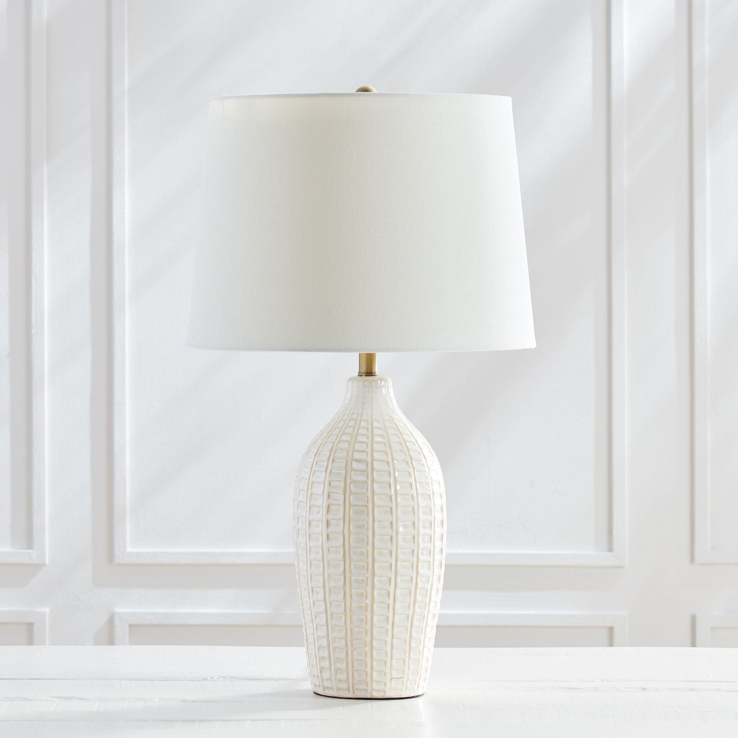 With a pressed pattern on the ceramic body, the Nadia Lamp is a work of art. Topped off with a generously scaled fabric shade, it is sure to enhance any space. intricate details, bold, finial, classic white, metal accents This ceramic lamp boasts an eye-catching pressed pattern and an elegantly designed fabric shade, making it an artistic addition to any room. With intricate details, a bold finial, and classic white coloring with metal accents, it offers both style and subtlety.