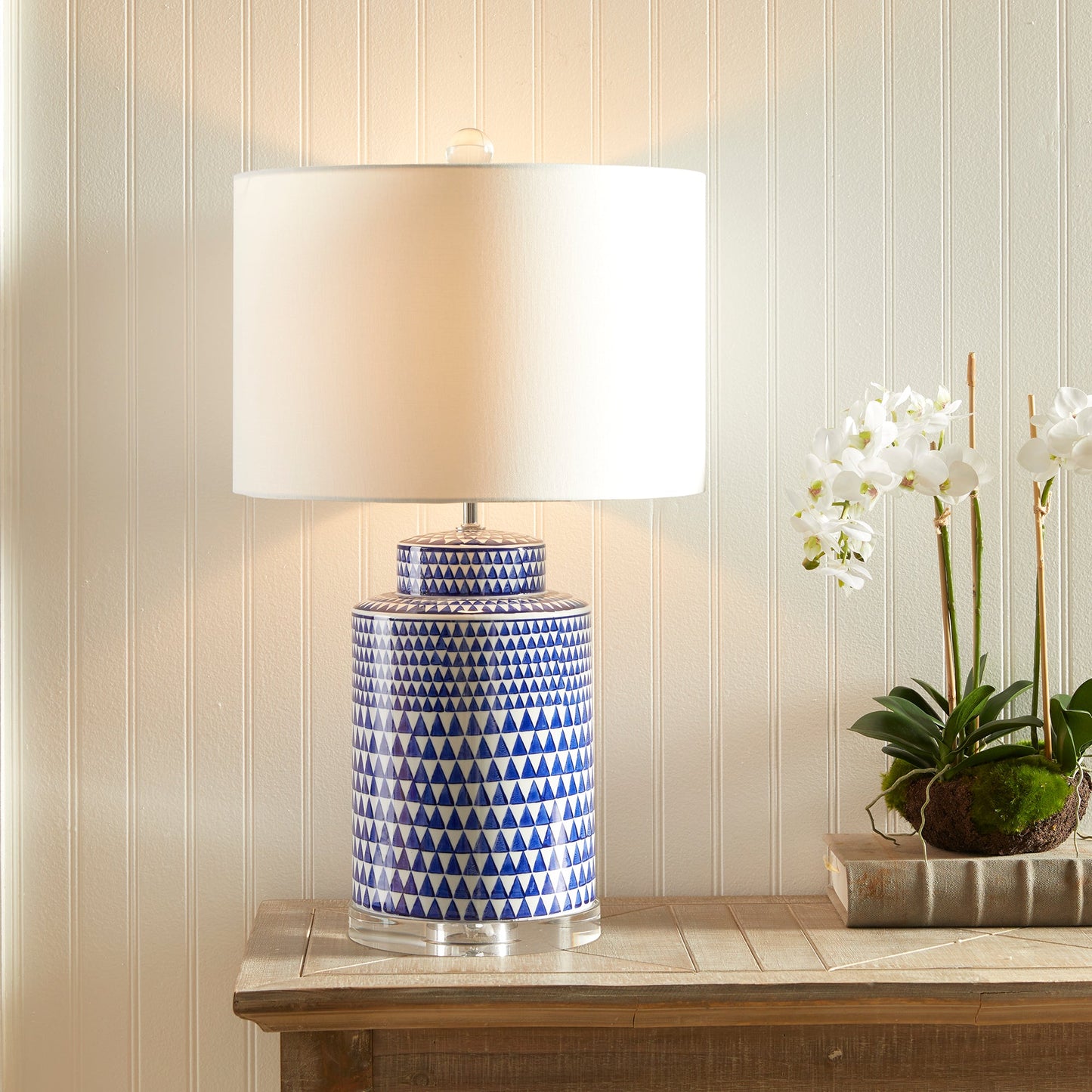 This table lamp features a traditional design in a classic blue and white ceramic ginger jar shape. Its elegant appearance adds a touch of blue to any traditional space. It also includes a crystal finial, weighs 16.5 lbs, and comes with a round shade.