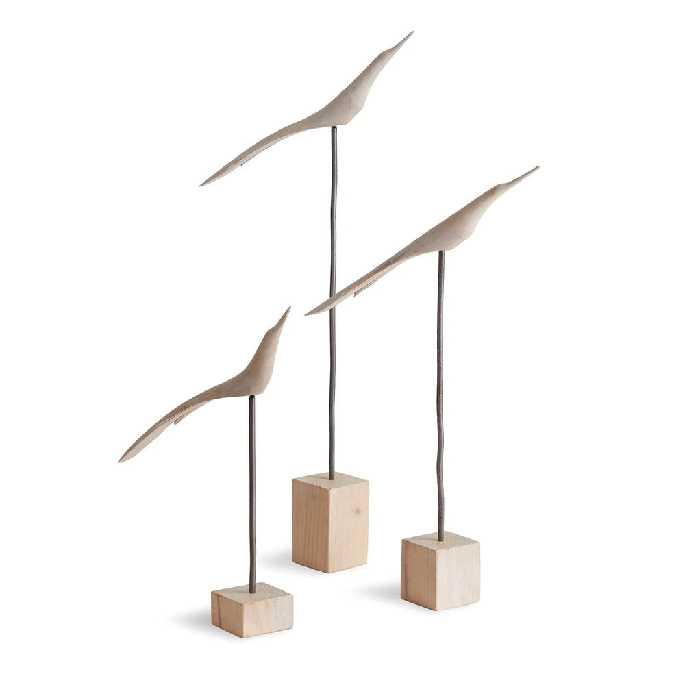 Three modern bird sculptures on wooden blocks against a white background