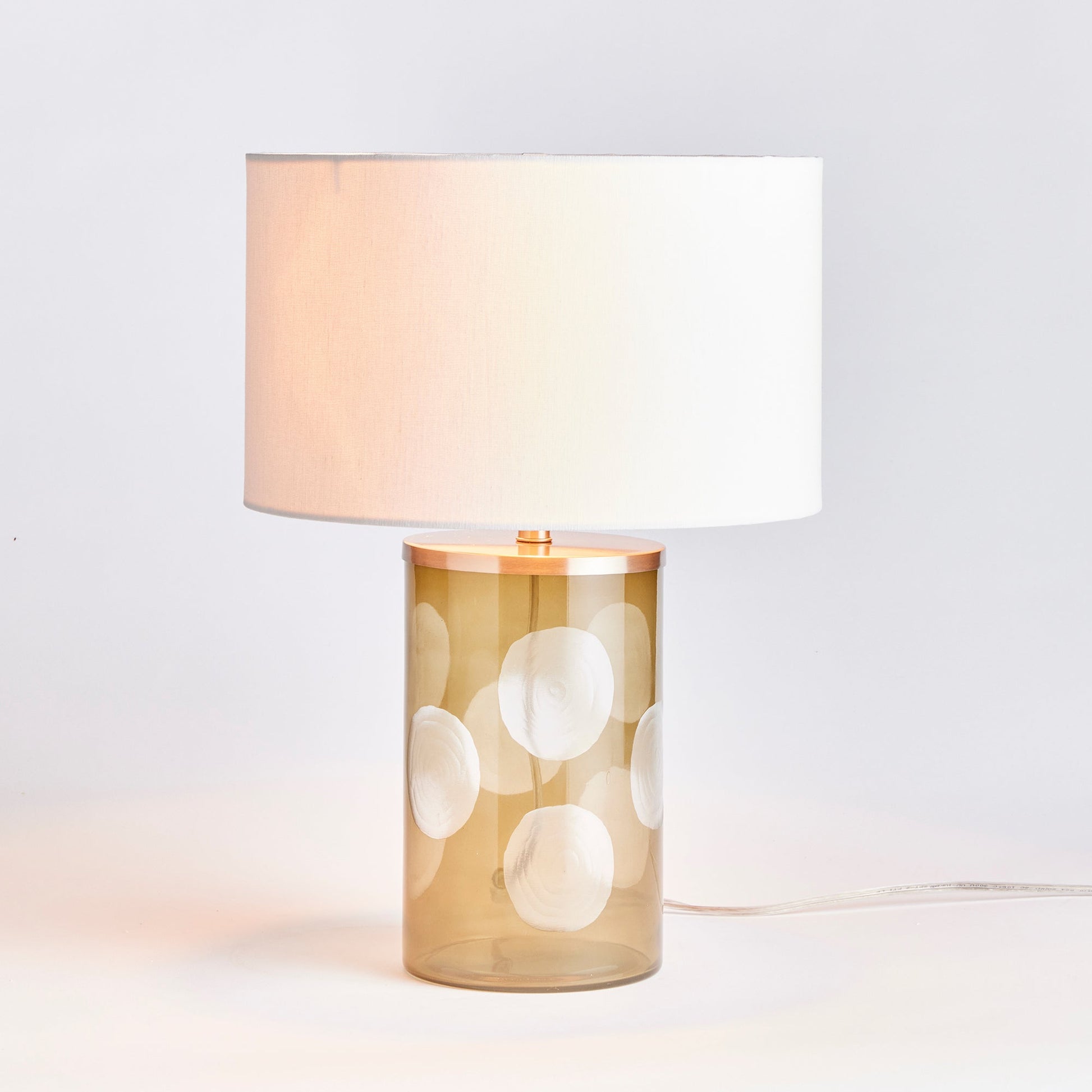 Enhance your home with the Norman Polka Dot Table Lamp, a playful addition that brings a touch of whimsy to any space. Crafted from soft taupe glass and featuring oversized etched polka dots, this lamp is finished with a bright white linen shade, making it a perfect accent for your console, desk, or side table.