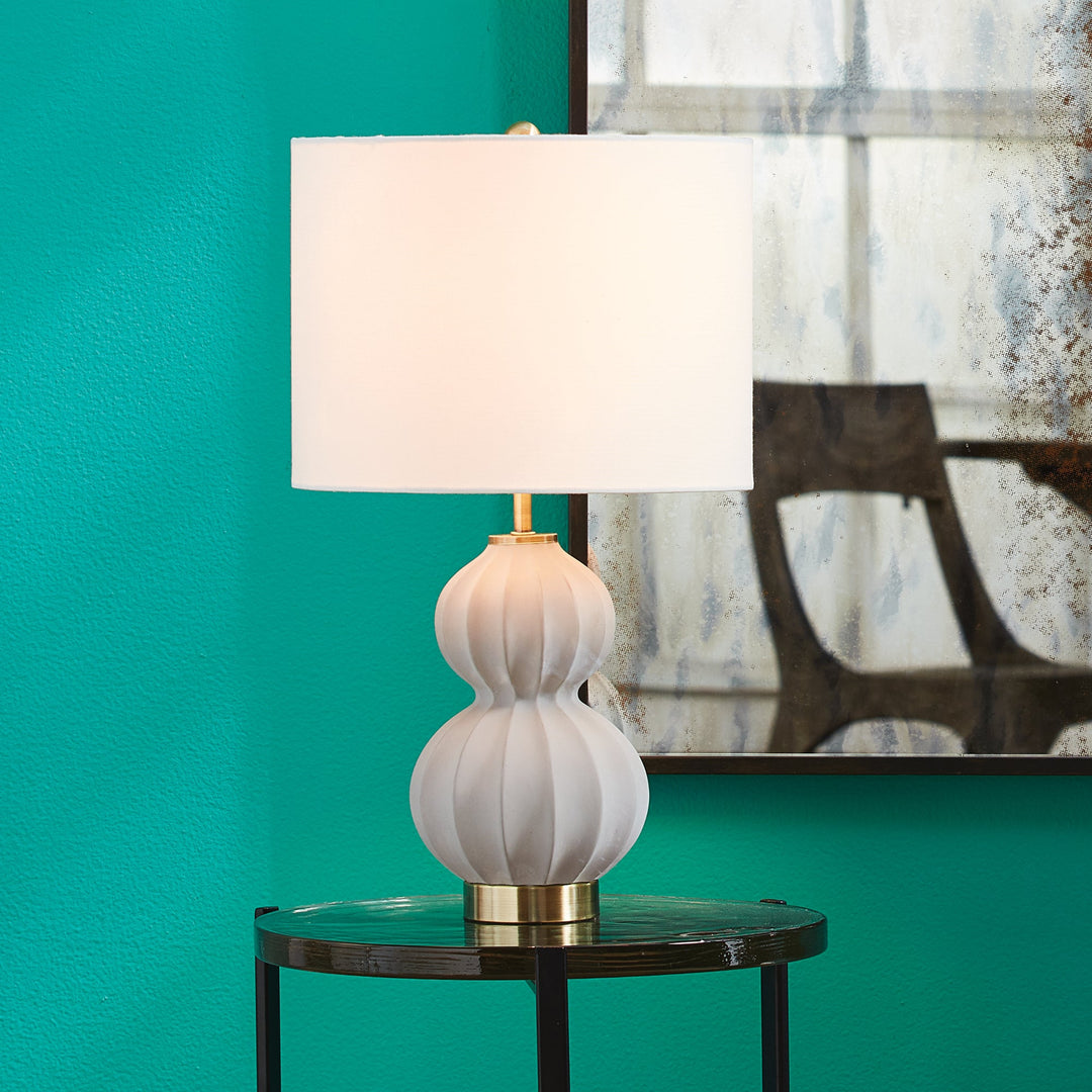 This elegant lamp blends seamlessly into any room, with its traditional yet transitional design featuring a classic natural concrete color and curvy shape. Its generous linen shade adds a touch of luxury, perfectly complementing the antique bronze accents