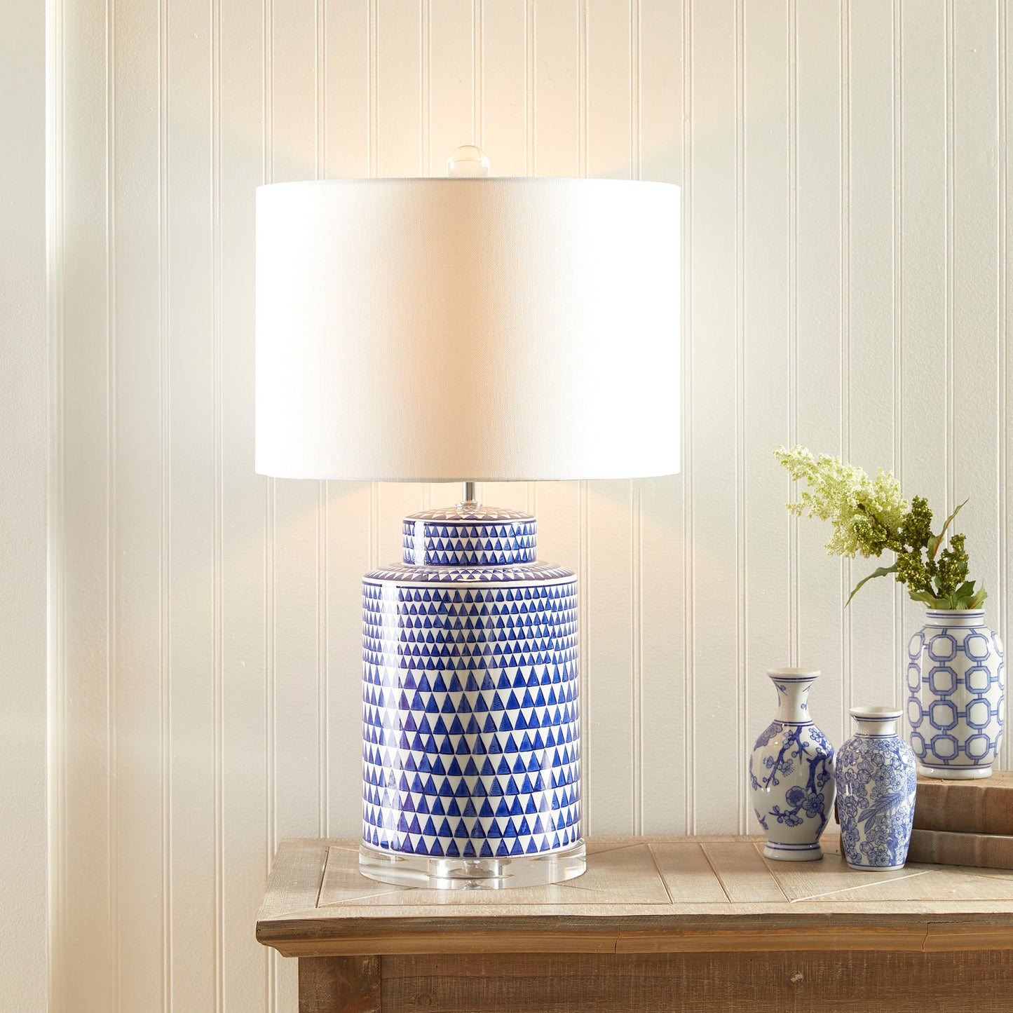 This table lamp features a traditional design in a classic blue and white ceramic ginger jar shape. Its elegant appearance adds a touch of blue to any traditional space. It also includes a crystal finial, weighs 16.5 lbs, and comes with a round shade.