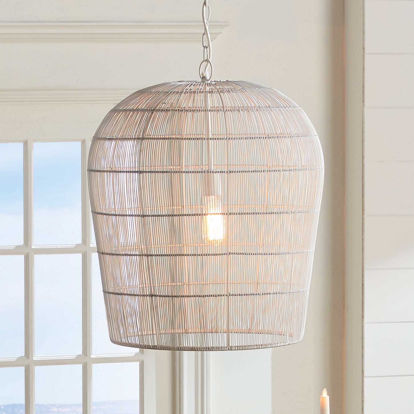 This pendant light features a solid iron frame that is elegantly wrapped in delicate white matte metal strands. With an open design, it brings a beautiful symphony of light, making it a great choice for placement in kitchens or foyer areas. Expertly crafted, it creates an elegant and grand aesthetic with its combination of materials.