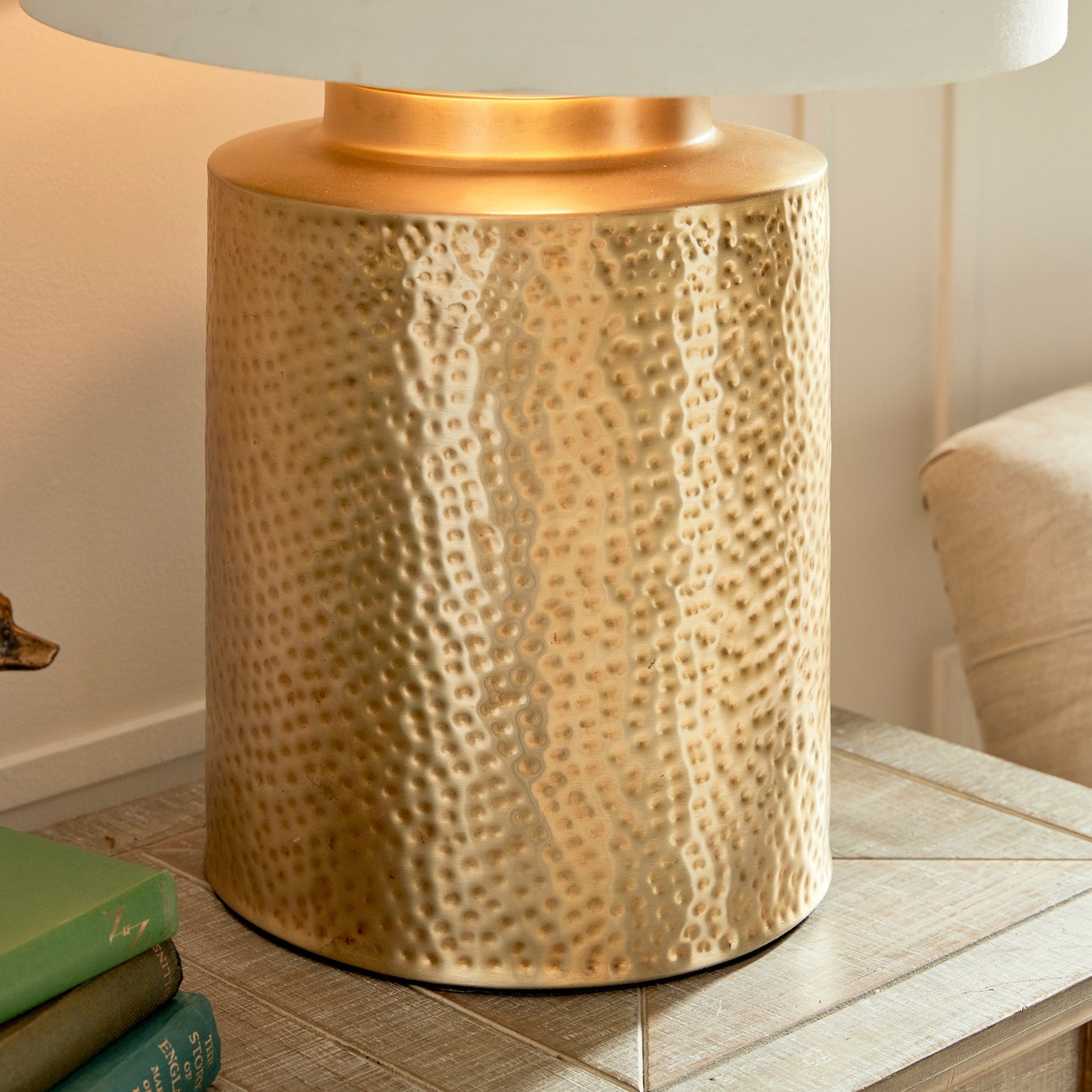 The Keegan Brass Table Lamp makes an impressive statement with its textured brass base and generous size, making it the perfect centerpiece for any space. The bold contrast is heightened by the white gallery shade with a gold inner shade, resulting in a striking and dramatic effect. Expertly crafted with intricate hammered detailing, this lamp is perfect for any living room, table, or living area.