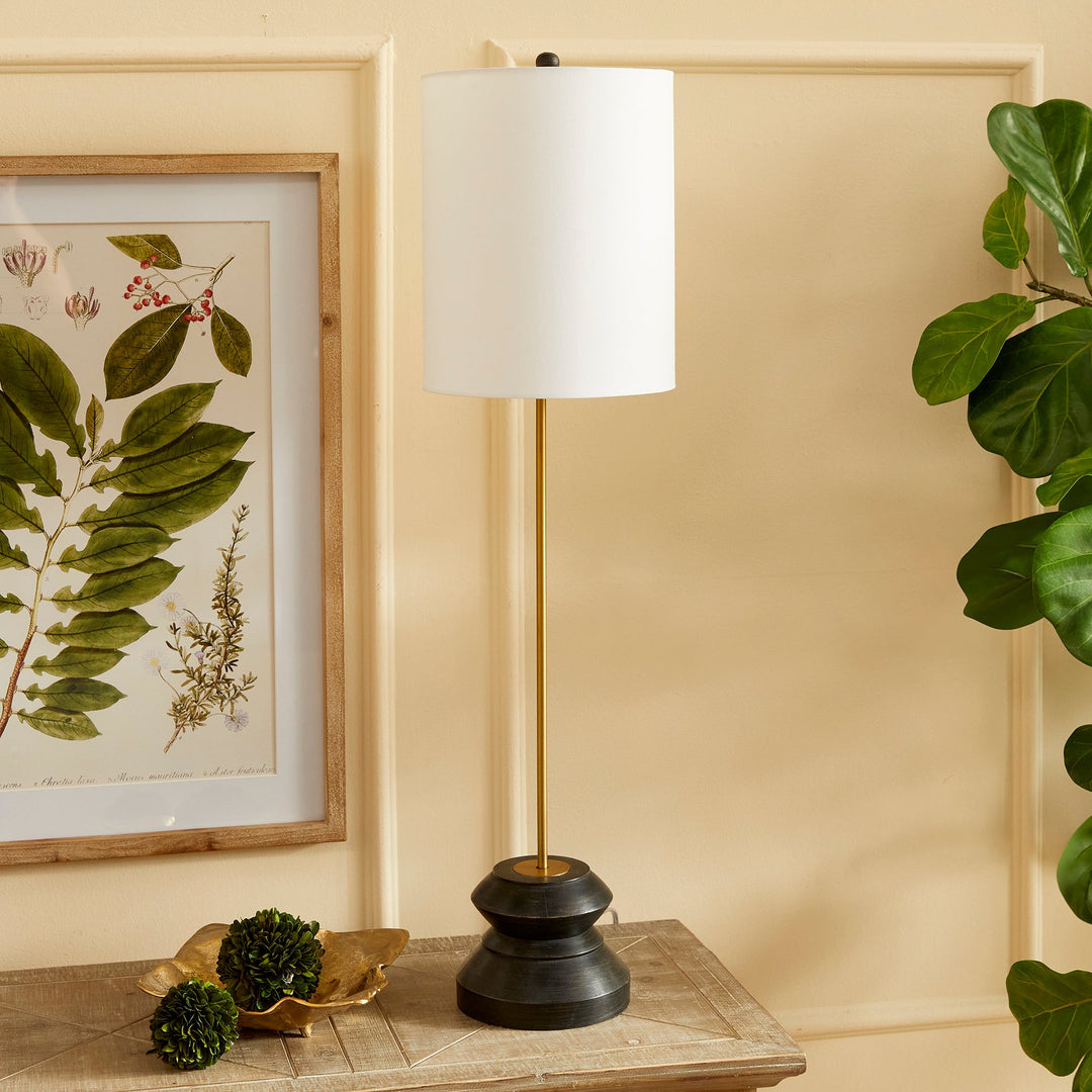 This tall, narrow lamp features a geometric turned wood black wash base, making it ideal for placement on either side of a long console or entry table. With its sleek and straightforward design, it provides a lovely way to illuminate a room with its soft light and black and gold accents, complemented by a linen shade.