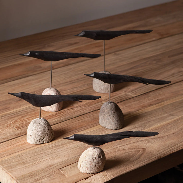 Decorative metal birds on stone bases on a wooden surface
