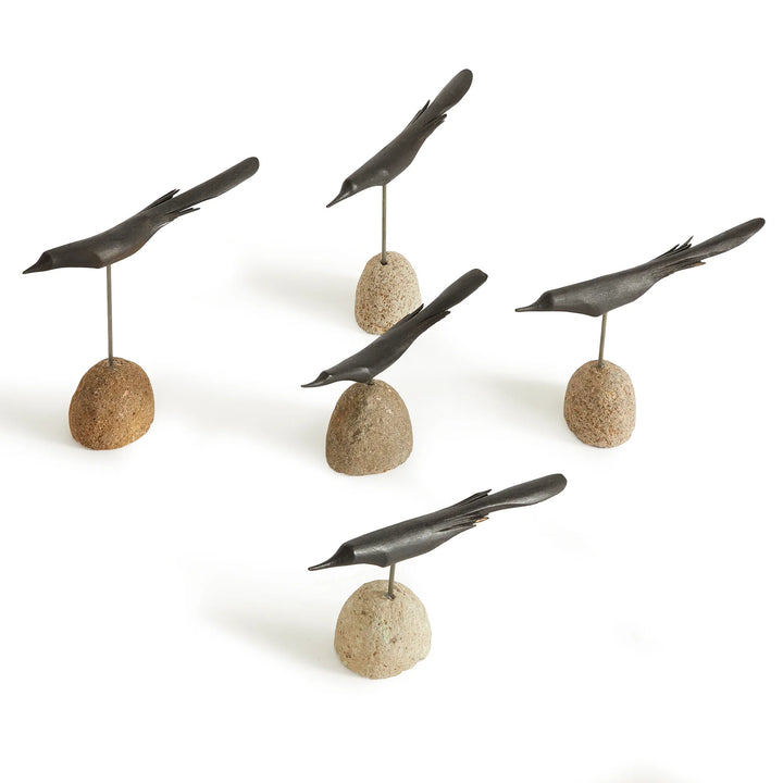 Set of five black bird sculptures on stone bases against a white background