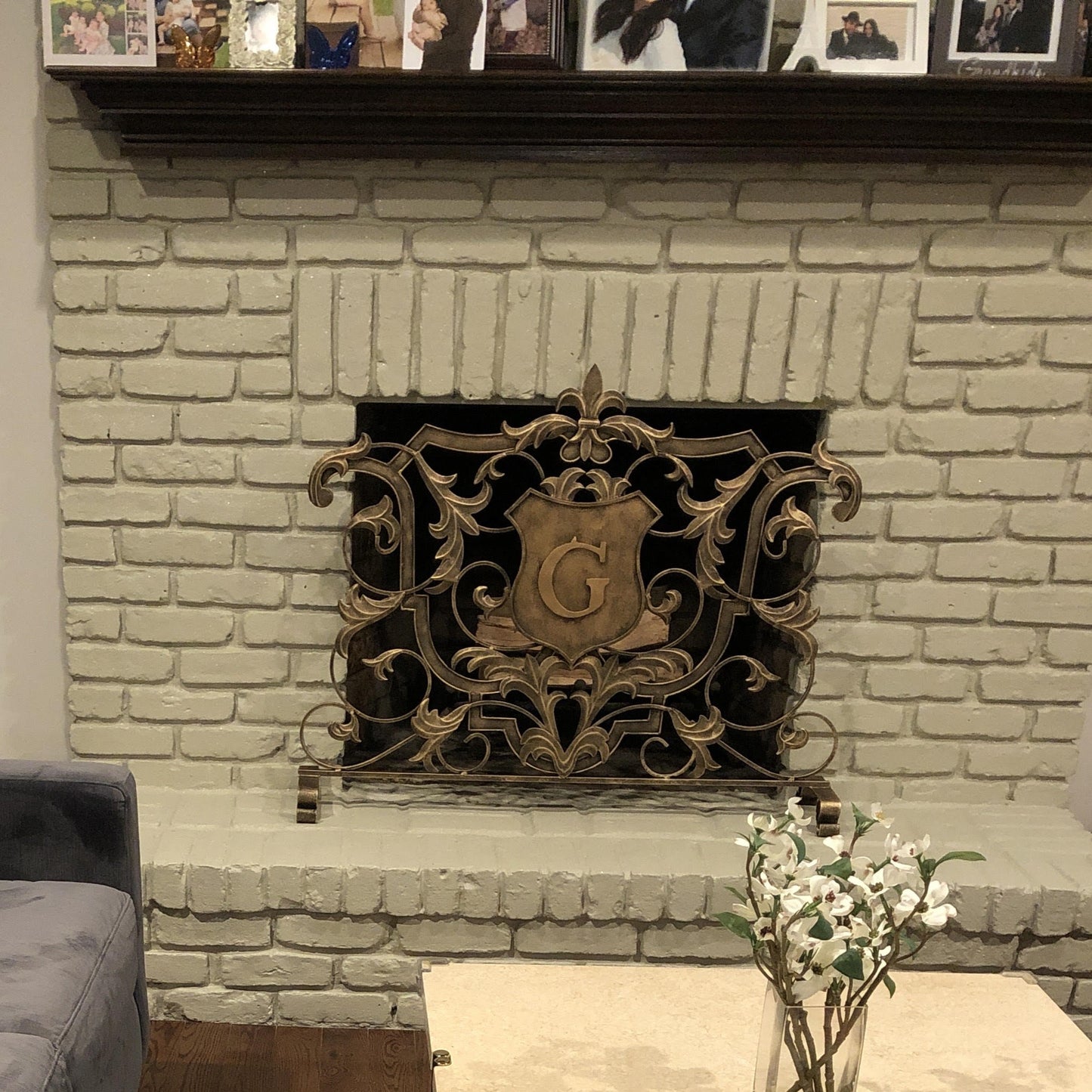 This single panel fireplace screen features contemporary styling and a custom, monogrammed letter in gold. The fixed legs provide stability and decorative flair, ensuring you can enjoy your cozy fire in style.