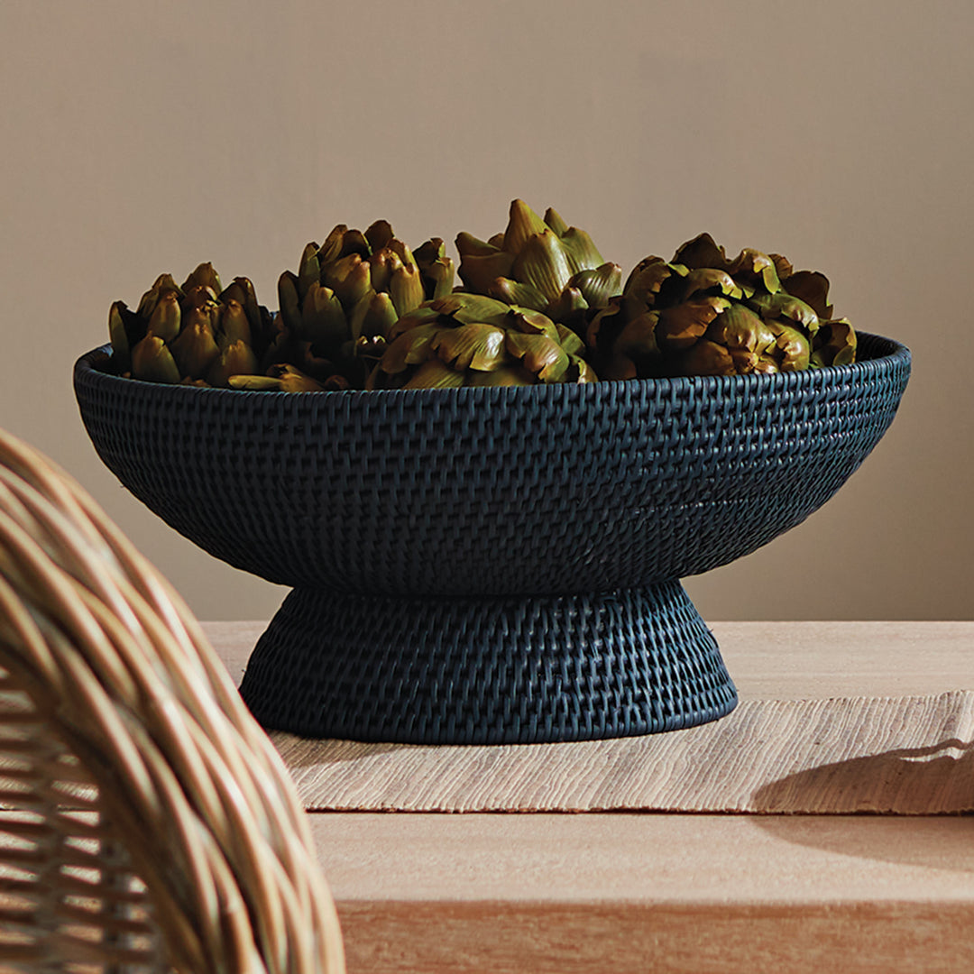 Dark blue woven rattan pedestal offering bowl filled with natural decorative accents on a styled wooden shelf, Transitional