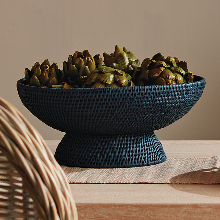 Dark blue woven rattan pedestal offering bowl filled with natural decorative accents on a styled wooden shelf, Transitional