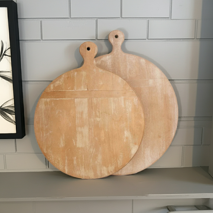 Set of two round whitewashed wooden cutting boards displayed on kitchen shelf with window light and pottery – Farmhouse Vintage