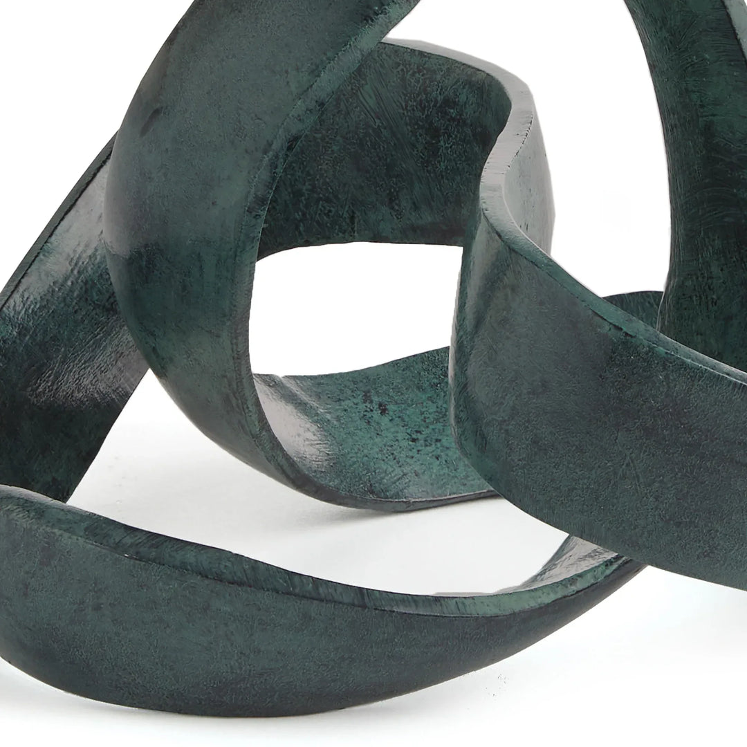 Close-up of a dark green abstract sculpture on a white background