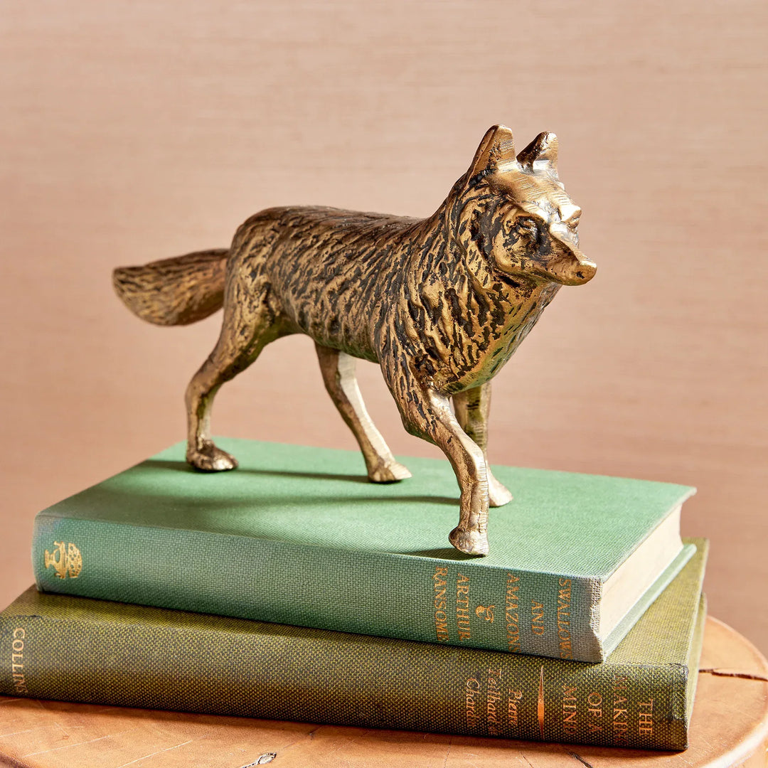 Bronze fox figurine on top of two stacked books with a beige background