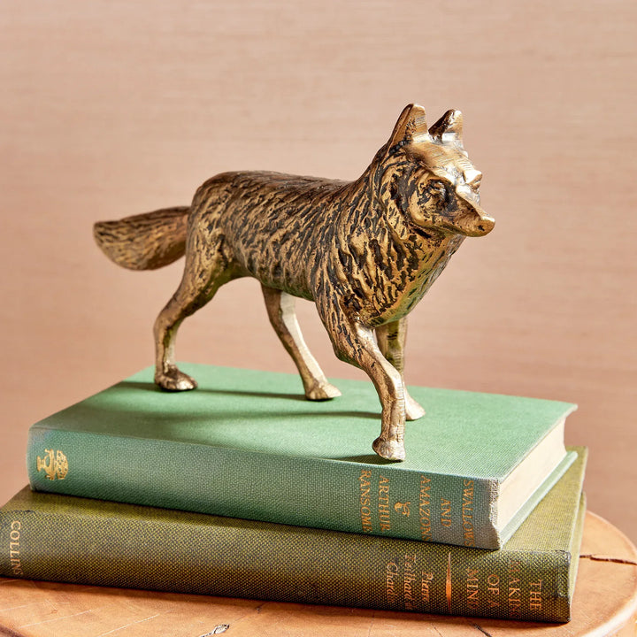 Bronze fox figurine on top of two stacked books with a beige background