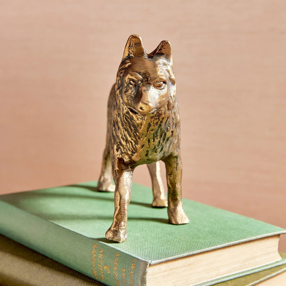 Bronze wolf figurine on a green book with a beige background