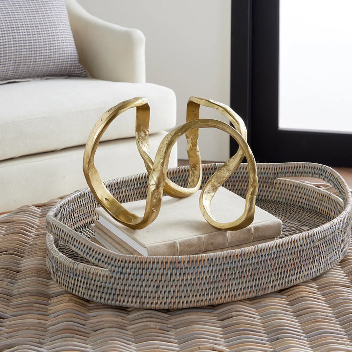 Decorative gold sculpture on a textured tray with a neutral background