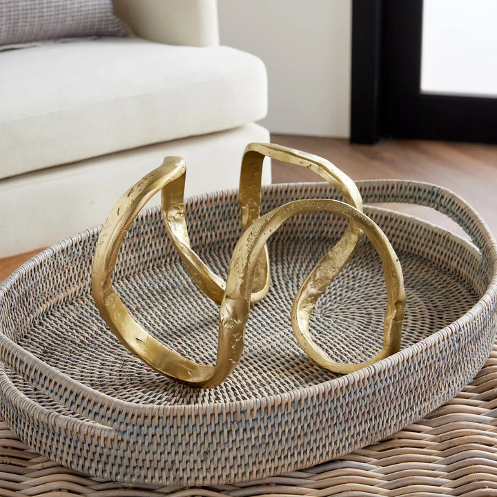 Gold decorative items on a woven tray in a living room setting