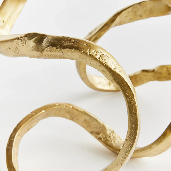 Gold decorative item with wavy design on a white background