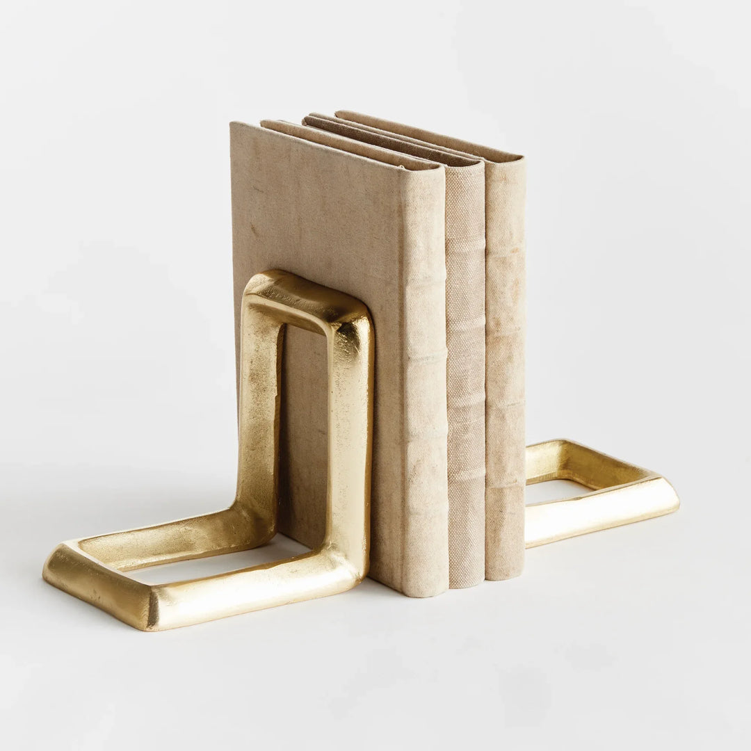 Brass bookends holding a book on a light gray background