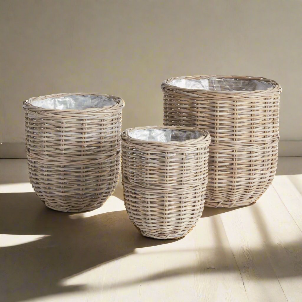 These assorted Gray Woven Basket Planters feature a unique warm gray finish achieved by soaking in mud and drying in the sun. Each planter is lined with plastic to ensure cleanliness and dryness. This set of three large baskets is perfect for coordinating all of your creative planting needs.