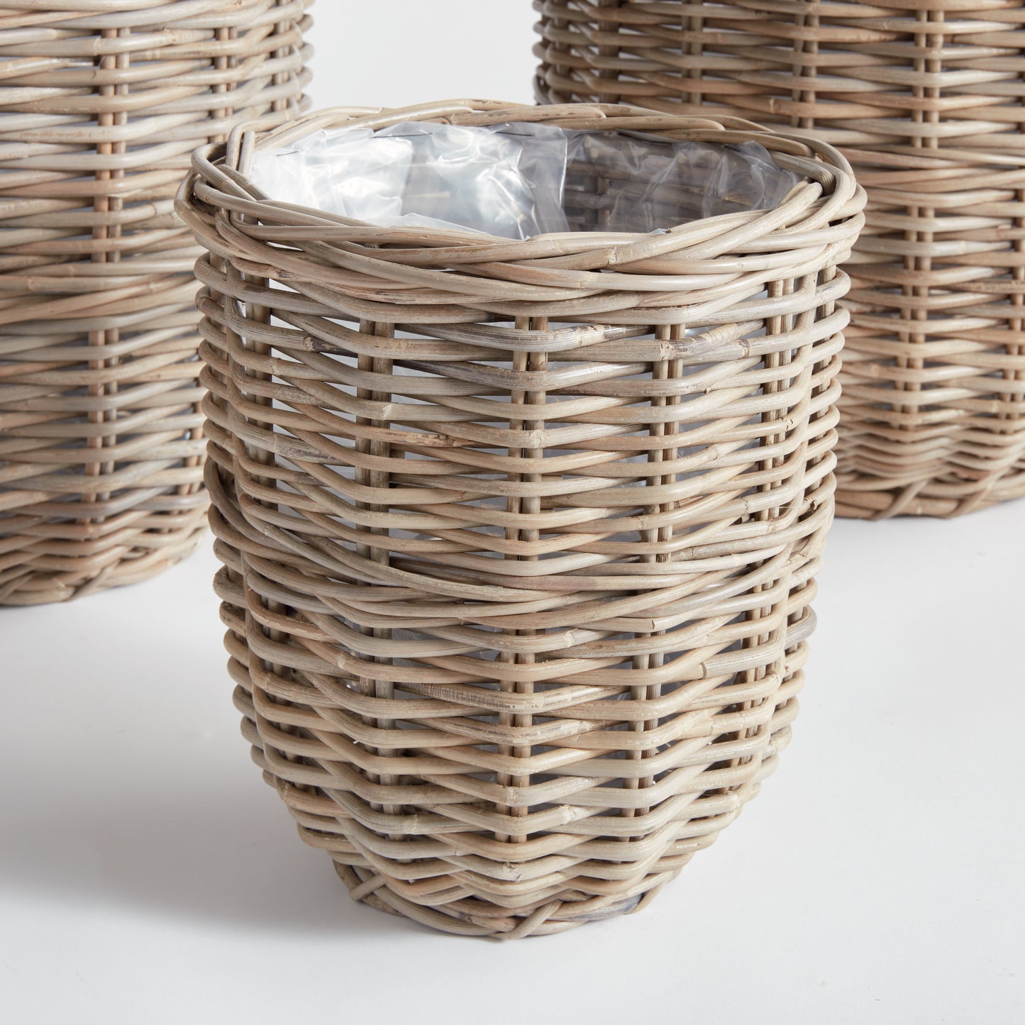 These assorted Gray Woven Basket Planters feature a unique warm gray finish achieved by soaking in mud and drying in the sun. Each planter is lined with plastic to ensure cleanliness and dryness. This set of three large baskets is perfect for coordinating all of your creative planting needs.