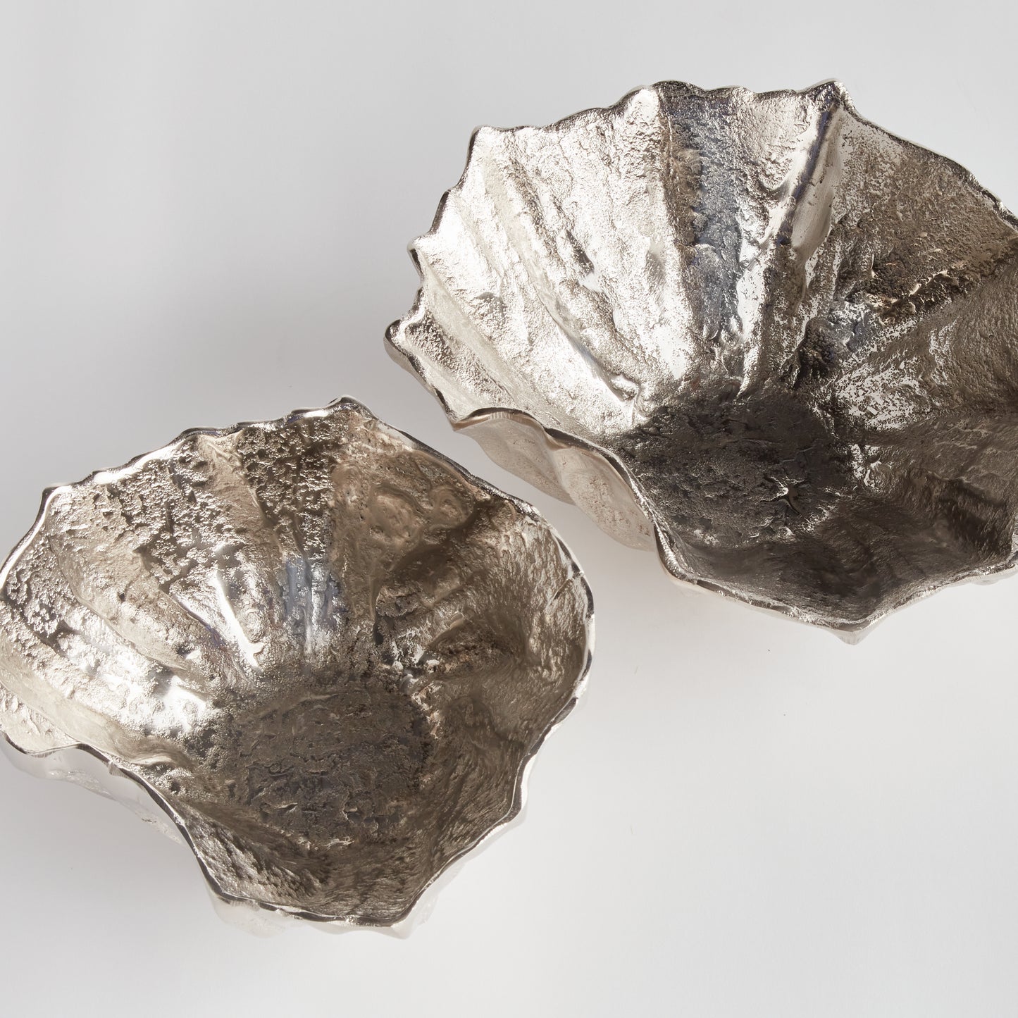 Crafted from durable cast aluminum, these rounded bowls are designed to resemble seashells. This coastal-inspired set can hold natural orbs or be used as beautiful standalone pieces. Perfect for dressing up your ottoman or side table, these Silver Seashell Decorative Bowls are expertly made with precision and inspired by the stunning beauty of coastal seashells.