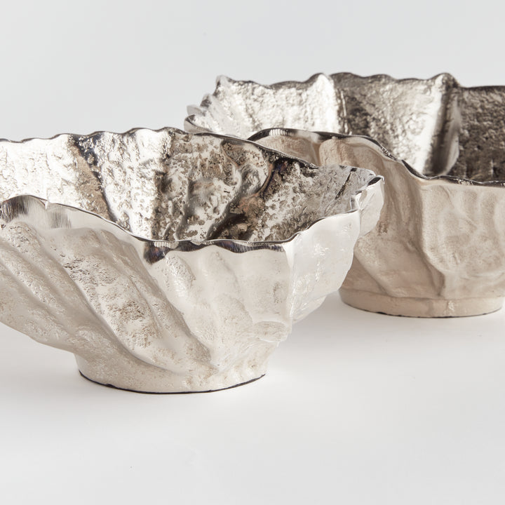 Crafted from durable cast aluminum, these rounded bowls are designed to resemble seashells. This coastal-inspired set can hold natural orbs or be used as beautiful standalone pieces. Perfect for dressing up your ottoman or side table, these Silver Seashell Decorative Bowls are expertly made with precision and inspired by the stunning beauty of coastal seashells.