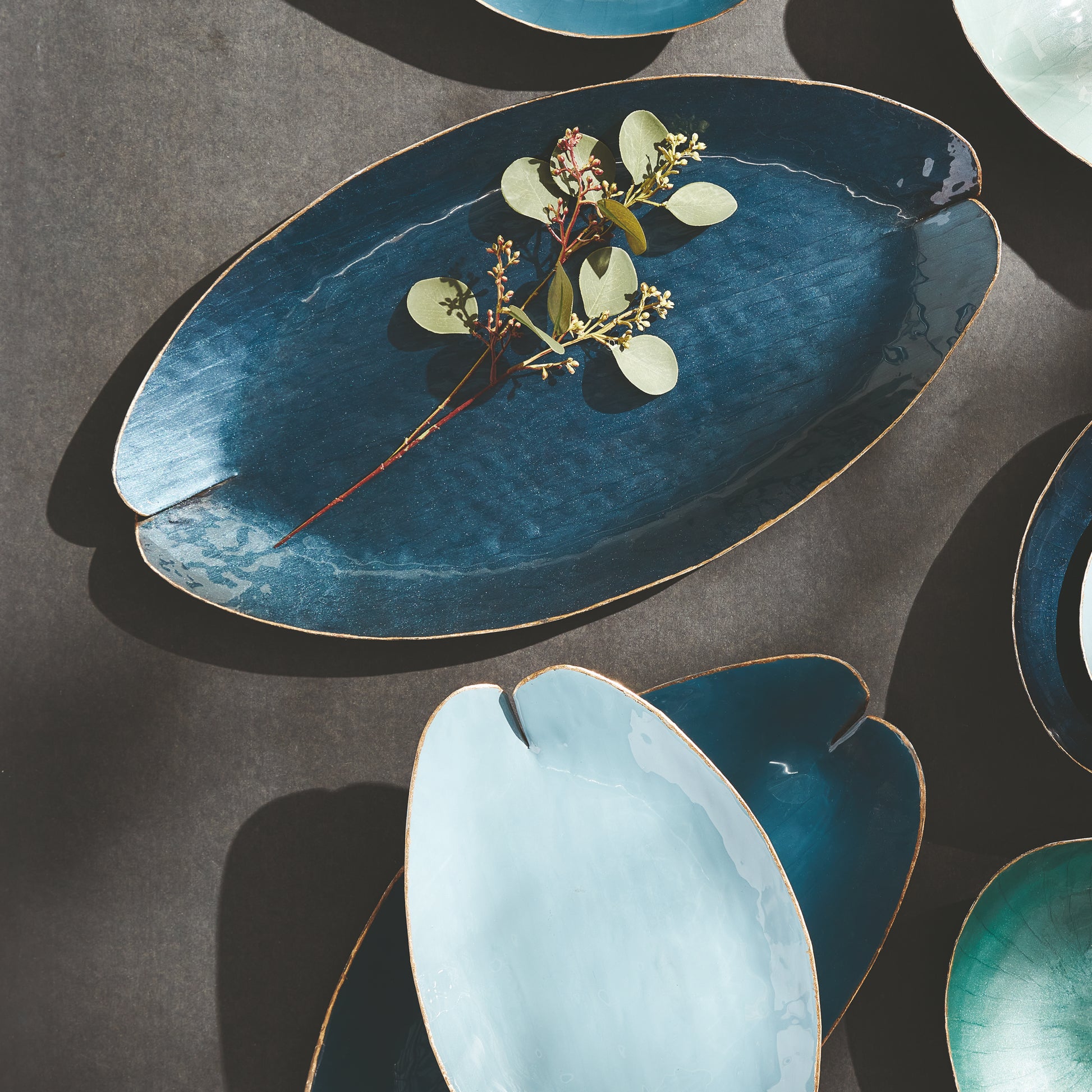 Elevate your home decor with our Camden Blue Coastal Decorative Trays. These expertly hand-painted trays feature a lily pad design and elegant gold edge detail, adding a touch of sophistication to any room. With coordinating soft blue hues, they can be used on a kitchen island, side table, or ottoman to add a pop of character. Each tray is both beautiful and functional, making them a versatile addition to any living space. Discover the charm and elegance of our hand-painted trays today.