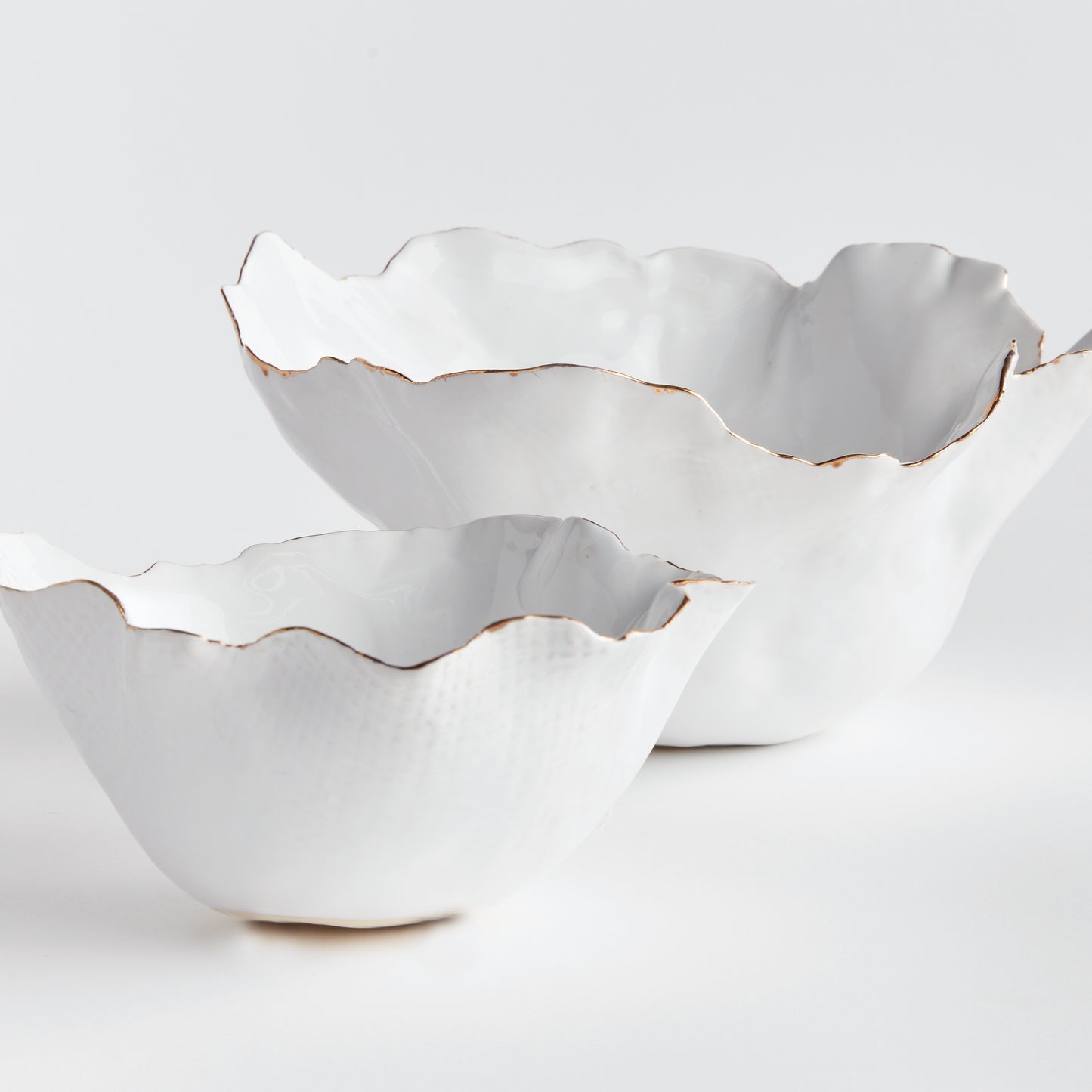 Add a touch of elegance to any room with these White Coastal Themed Decorative Bowls. The crimped edges and natural form create a stunning centerpiece, while the hand-brushed gold tipped edges add shine and durability thanks to the electroplating process. Whether displayed on a coffee table with art books or on a side table, these bowls are both functional and beautiful.