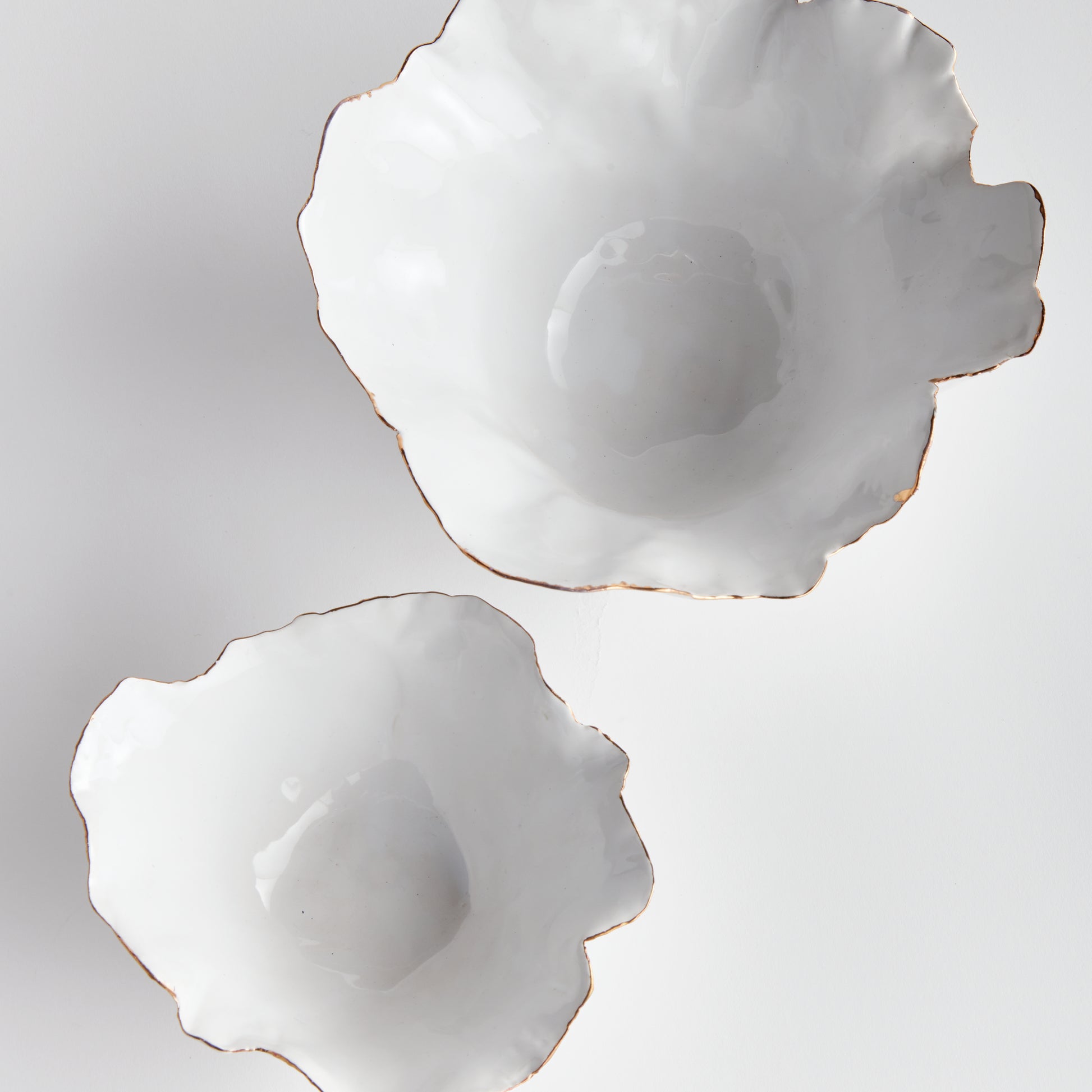 Add a touch of elegance to any room with these White Coastal Themed Decorative Bowls. The crimped edges and natural form create a stunning centerpiece, while the hand-brushed gold tipped edges add shine and durability thanks to the electroplating process. Whether displayed on a coffee table with art books or on a side table, these bowls are both functional and beautiful.