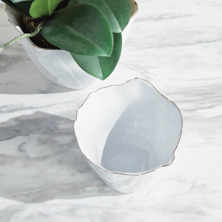 Our White Cachepots Planters feature crimped edges and a natural form, making them the perfect statement-making centerpiece. The hand-brushed gold tipped edges are electroplated for lasting shine and durability. Add your favorite orchid to elevate your home decor game.