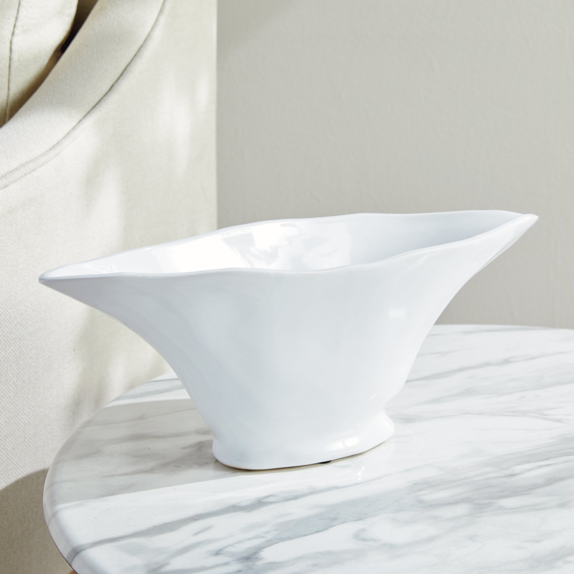 Enhance the aesthetic of any space with this coastal themed white oval vase. Its sculptural form and slim profile are ideal for a narrow console or mantle. Add elegance by draping faux stems or filling it with decorative orbs. Create a unique focal point and elevate your home decor effortlessly.