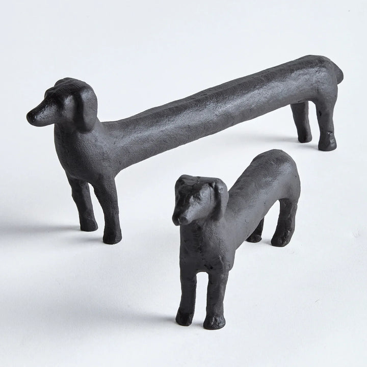 Two black dog sculptures on a white background