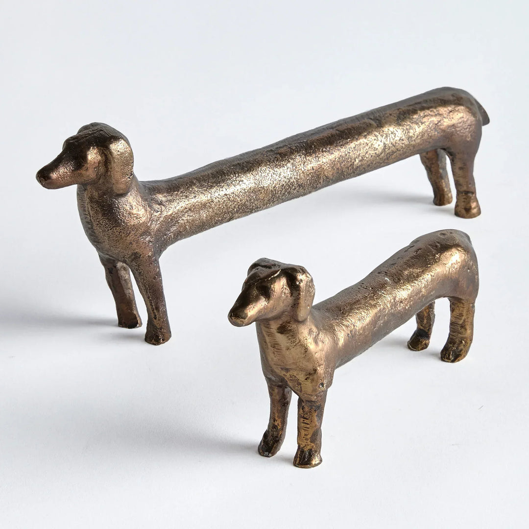 Two bronze dog sculptures on a white background