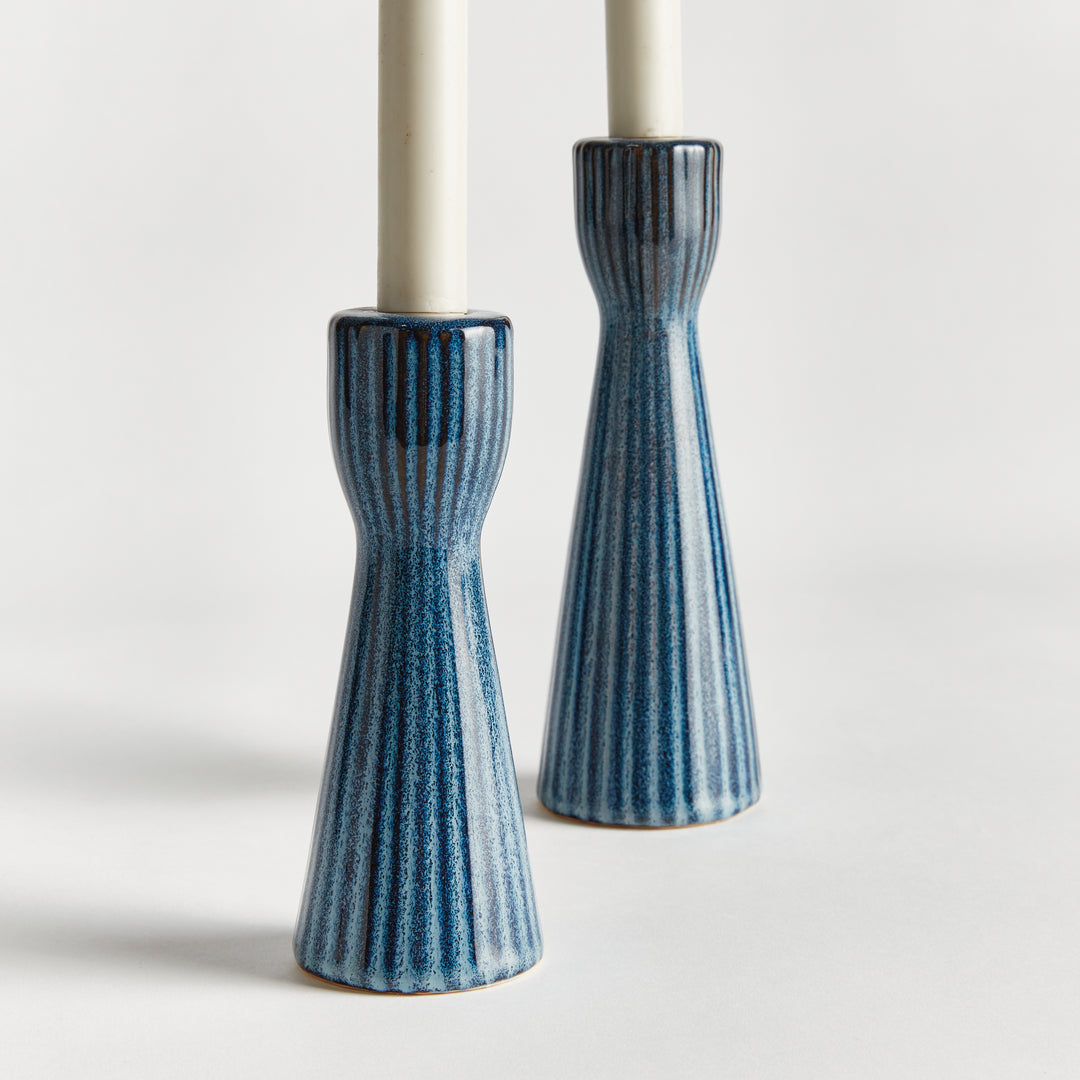 Blue stoneware candle holders shown with warm ambient lighting