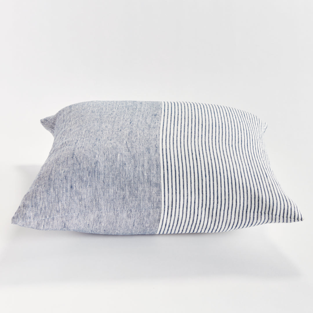 24-inch striped linen pillow in navy and ivory shown on light-toned furniture in natural lighting


