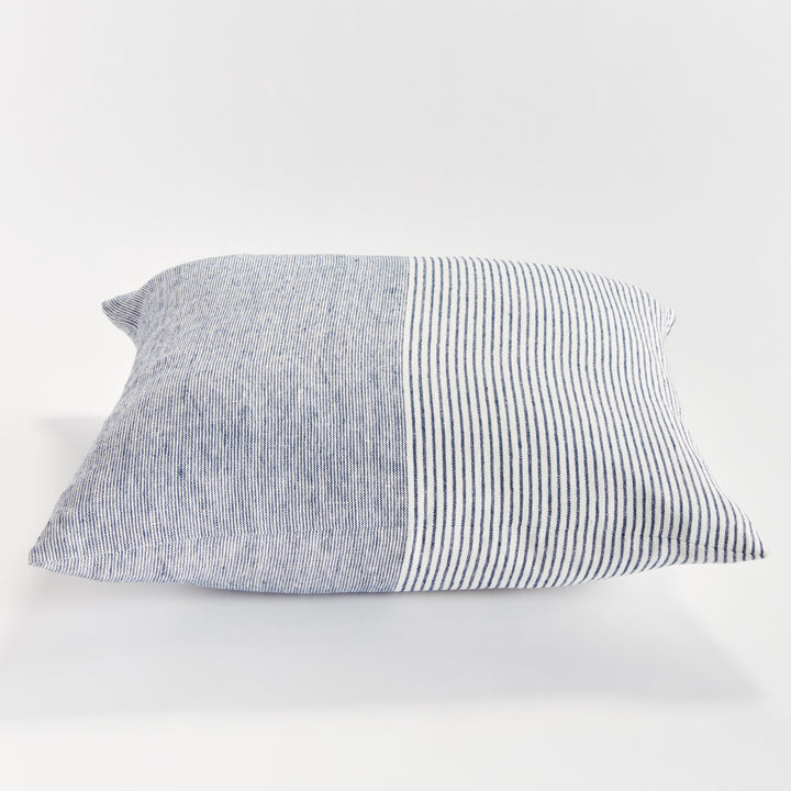 24-inch striped linen pillow in navy and ivory shown on light-toned furniture in natural lighting


