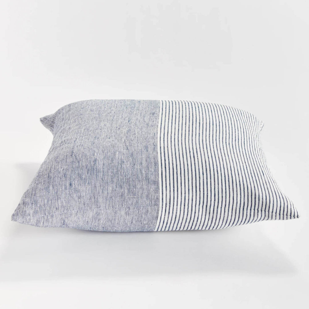24-inch striped linen pillow in navy and ivory shown on light-toned furniture in natural lighting


