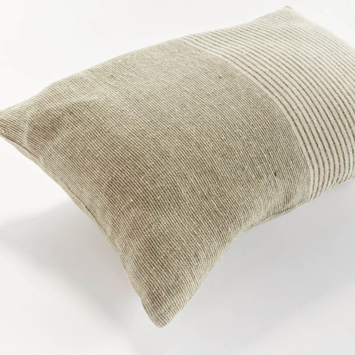 Delamere lumbar pillow in green and flax placed at the center of a softly layered bedscape, adding structured calm to a coastal-inspired bedroom.

