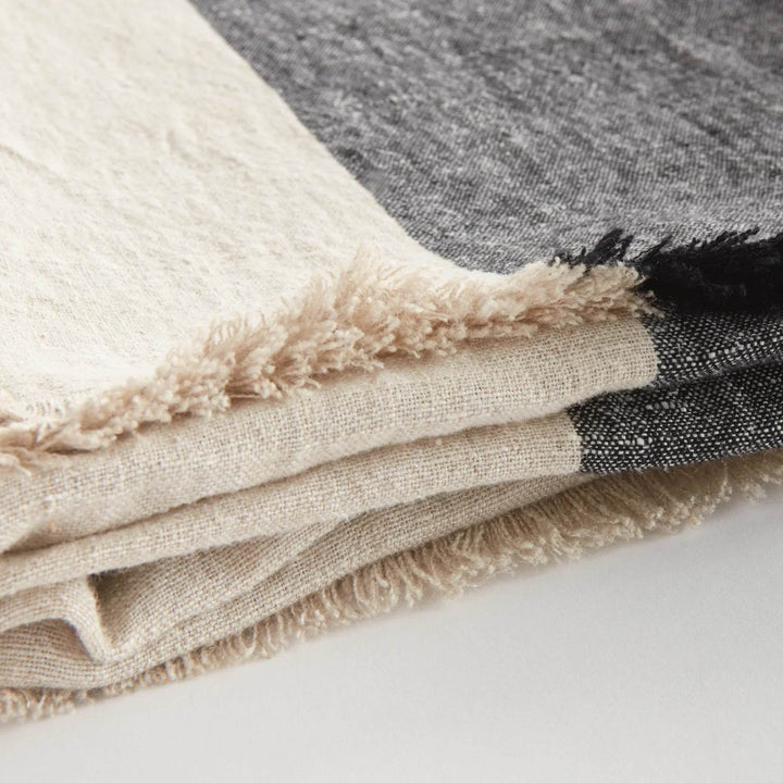 Close-up of linen throw blanket edge showing soft frayed fringe and weave pattern

