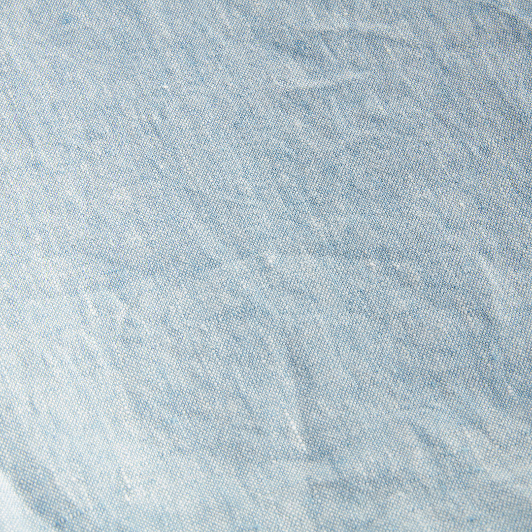 Angled view of light blue European linen throw showing soft frayed edge and layered fabric, ideal for home styling.