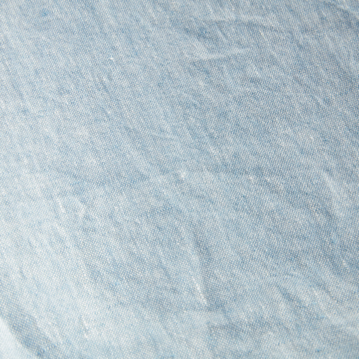 Angled view of light blue European linen throw showing soft frayed edge and layered fabric, ideal for home styling.