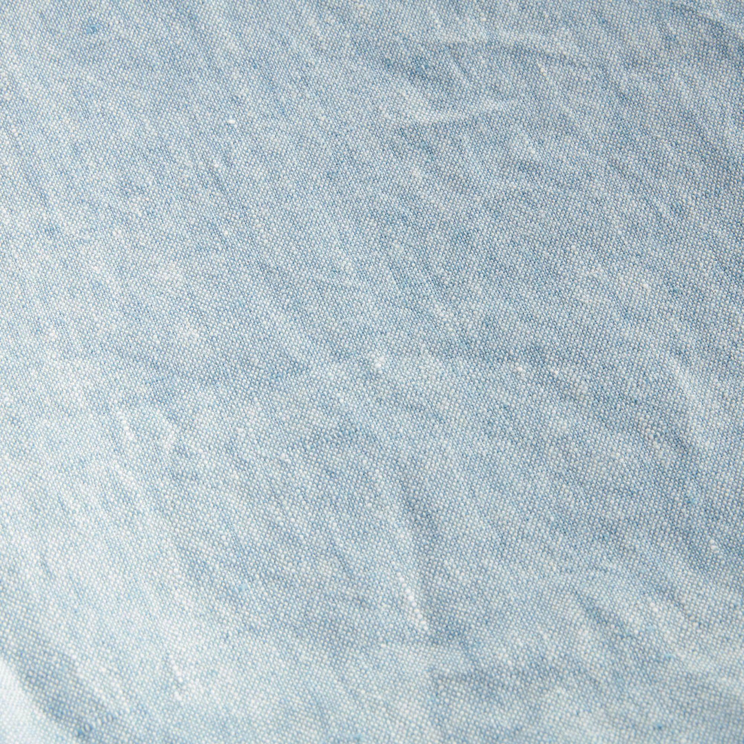 Angled view of light blue European linen throw showing soft frayed edge and layered fabric, ideal for home styling.