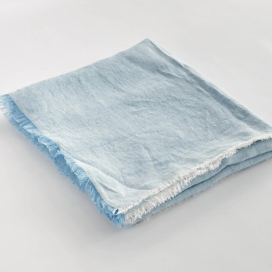 Angled view of light blue European linen throw showing soft frayed edge and layered fabric, ideal for home styling.