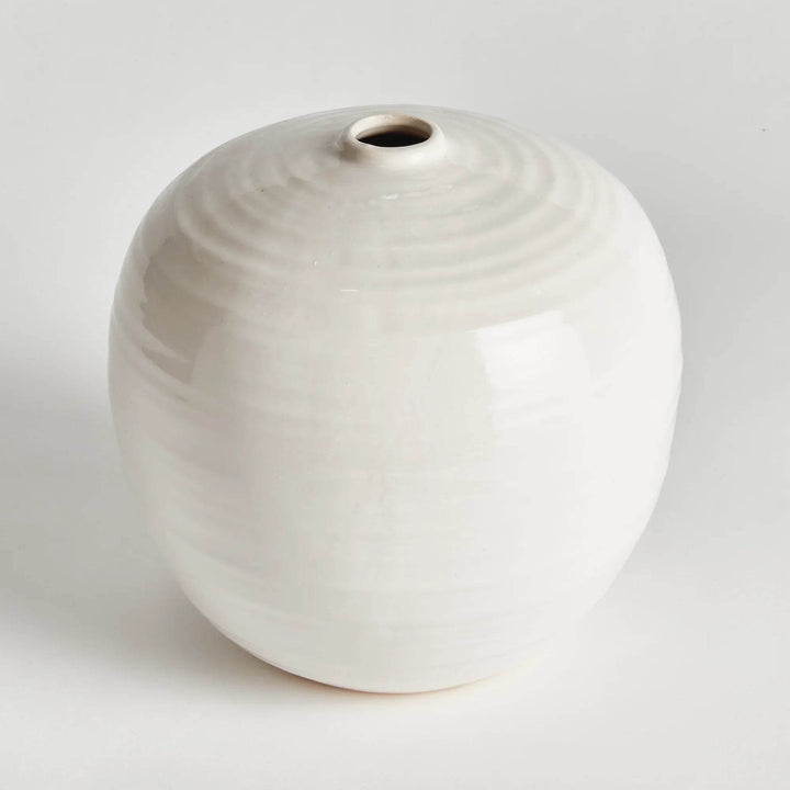 “Small oatmeal stoneware vase with a round silhouette and reactive glaze finish, displayed against a clean white background.”

